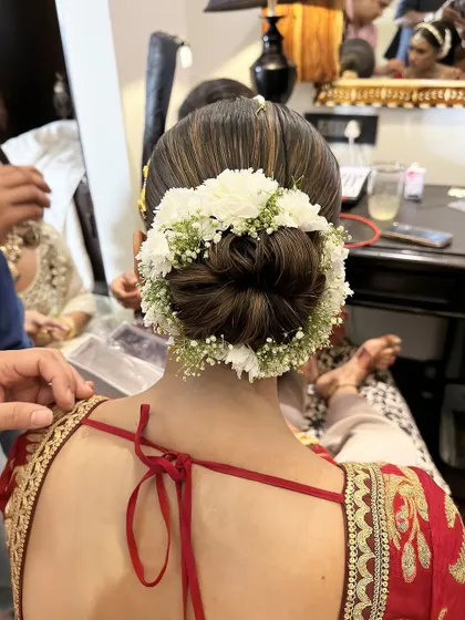 A classic Sabyasachi bride look with a clean, traditional bun adorned with a halo of fresh white flowers.