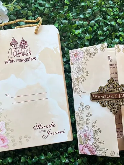 This invitation set includes a matching carry bag and a gate-fold card with a floral design and a custom metal clasp.