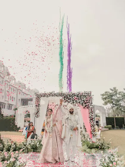 A grand celebration moment with the couple under a shower of petals and colorful smoke, creating a vibrant and joyful memory.