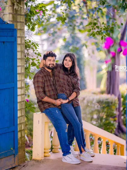 A happy, relaxed portrait of a couple on a balcony. Their matching plaid shirts and denim create a fun, coordinated look.