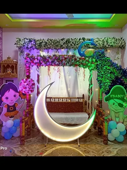 The peacock-themed baby shower decoration with green and blue lighting, highlighting the intricate floral work of the peacock.