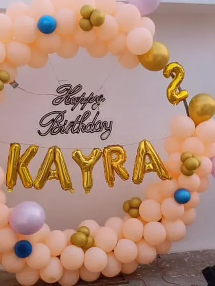 A lovely pastel-colored ring decoration for Kayra's second birthday. This outdoor setup uses a full balloon circle with the name in gold foil letters, perfect for a terrace or garden party.