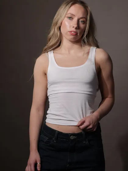 A simple yet strong portfolio shot featuring a white tank top and denim. The lighting is soft but directional, highlighting the model's features and physique.