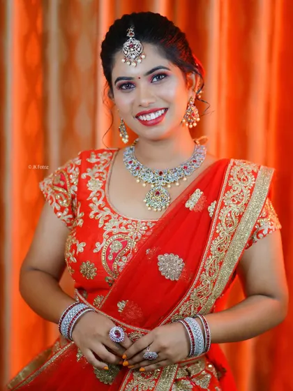 A happy bride posing in our red and gold embroidered lehenga. This outfit is paired with a sparkling AD stone jewellery set, also available for rent.