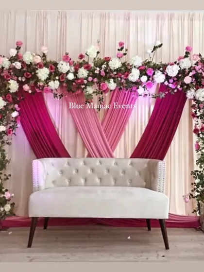 A stunning engagement stage with a floral arch in shades of pink and white. The layered pink drapes add depth and richness to the design, perfect for a grand celebration.