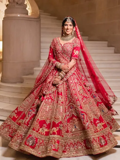 A magnificent full-length portrait showcasing a bride in a stunning red lehenga. The makeup is designed to be grand yet elegant, perfect for a palace wedding.
