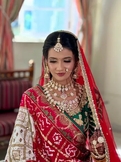 A classic portrait of the bride in her red and green bridal attire, with makeup that highlights her features beautifully.