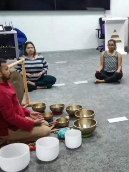 I guide employees through a seated meditation, surrounded by Himalayan and crystal singing bowls. This image shows the simplicity and accessibility of the practice within a standard office setting.