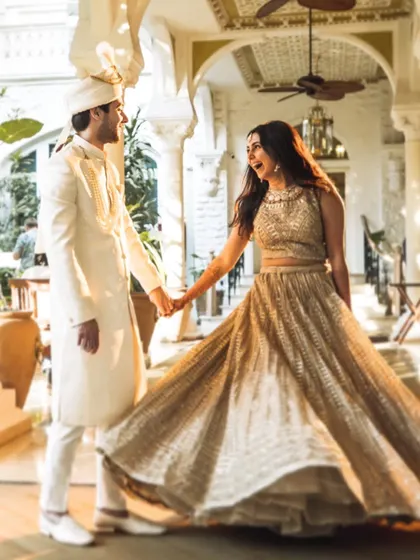 A beautiful, candid moment from a wedding celebration at the Taj Palace Hotel. The bride's twirling lehenga and the couple's happy expressions create a perfect sense of motion and joy.