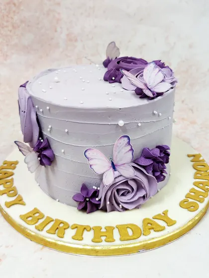 We create a dreamy vision with this lavender butterfly cake. A cascade of purple buttercream roses and delicate, edible butterflies adorns the textured lavender frosting, accented with tiny pearls for a touch of magic and elegance.