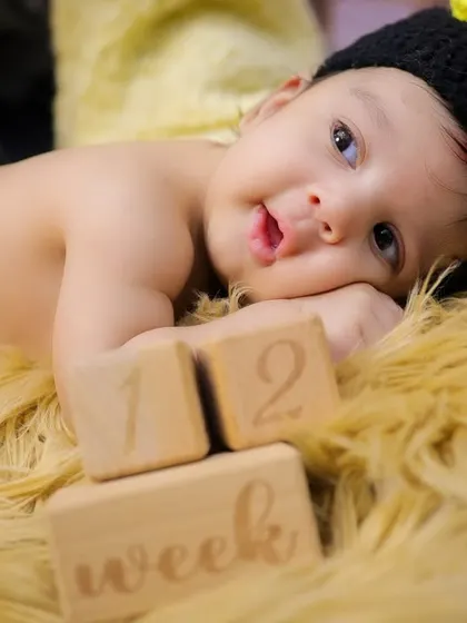 Marking the early weeks with wooden milestone blocks. This baby, dressed in a bee costume, shows how we can track your baby's growth even in the first month.