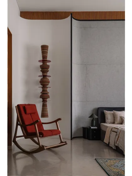 A wider shot of the parent's bedroom, showing the simple, elegant bed and the beautiful play of textures between the fabric headboard, wooden furniture, and concrete-finish wall.