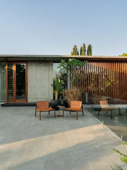 The upper terrace of the Long House, a private outdoor space defined by exposed concrete, a glass railing, and a slatted timber privacy screen.