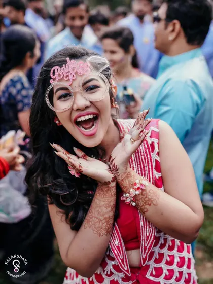 Pure excitement! A bride-to-be wearing fun "Bride to Be" glasses at her Haldi party.