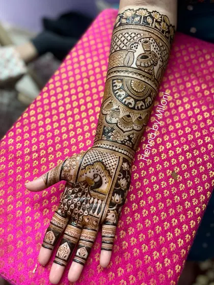 A detailed bridal mehendi with peacocks on the palms and elephants on the wrists. The fine line work and shading add depth and dimension to the design.