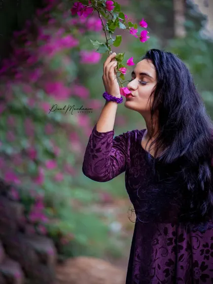 The rich purple of her dress against the vibrant blue wall and bougainvillea creates a stunning color combination. This is a perfect example of using the environment to make your portraits stand out.