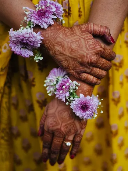 A close-up of the bride's geometric mehendi design, complemented by fresh floral jewelry. This shows how we can blend modern patterns with traditional elements.