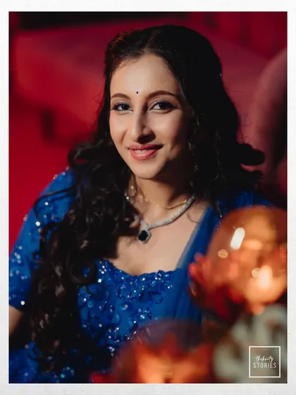 A lovely portrait of the bride at her Sangeet, her smile lighting up the frame. The vibrant blue of her outfit adds a pop of color to the festive atmosphere.
