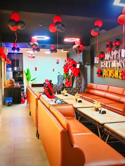 A full view of a restaurant decorated for a birthday party. The red and black balloons match the modern decor of the space, creating a cohesive look.