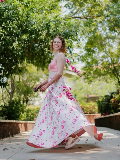 For their welcome event in Goa, we went with an easy-breezy look. The bride is wearing a custom Banarasi lehenga skirt with a pop of pink, paired with comfy sneakers for a fun, contemporary twist.