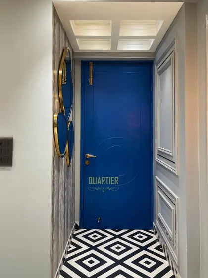 The entrance foyer at the Elite Golf Greens project makes a bold statement with its vibrant blue door and black-and-white geometric floor tiles. The design immediately establishes the home's unique, modern European character.