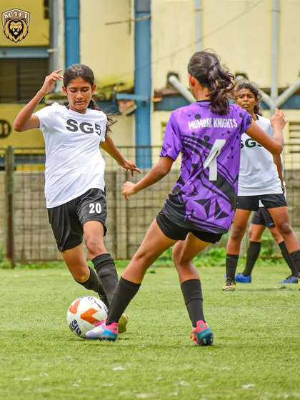 A player from our girls' team skillfully shielding the ball from a Mumbai Knights opponent during a league match.