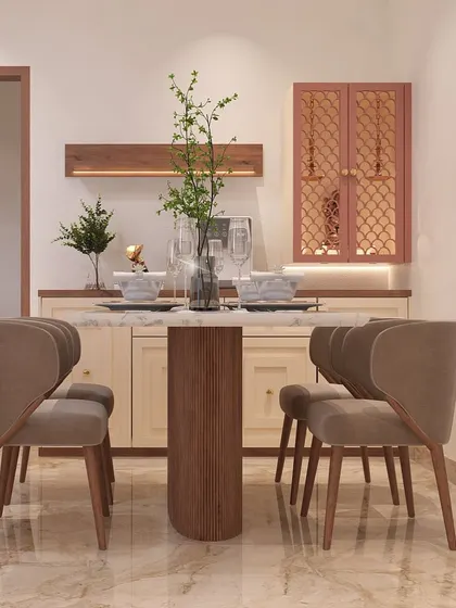 This dining space is designed for cozy meals. The four-seater table with a fluted wood base is complemented by a custom-built crockery and pooja unit in the background, featuring lattice-work doors.