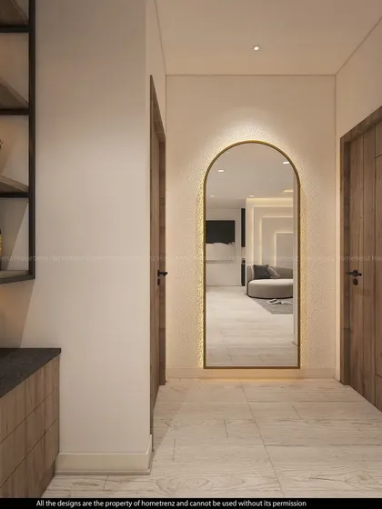 A hallway featuring a bar and storage area on one side and an elegant, arched, back-lit mirror on the other.