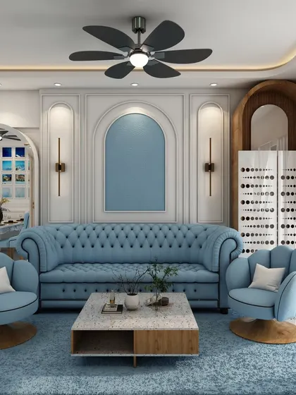 A full view of the blue-themed living room, showing the tufted Chesterfield sofa, matching armchairs, and a large mirror that reflects the dining area, making the space feel larger.