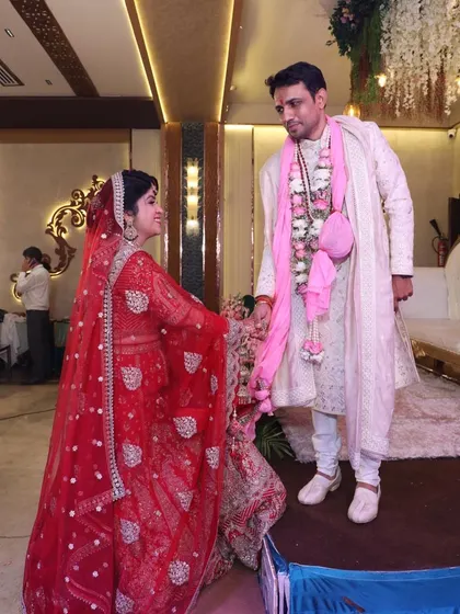 A candid moment from Richa and Puneet's wedding, showcasing the bride in her vibrant red lehenga and the groom in a classic sherwani. Their interaction reflects the joy and ease that comes with finding a like-minded partner.