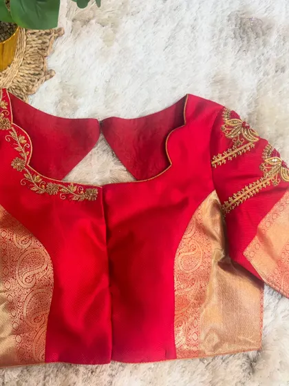 The front of the red blouse, featuring a unique collar-like neckline design with delicate gold embroidery.