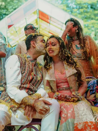 A sweet kiss amidst the playful mess of the Haldi ceremony.