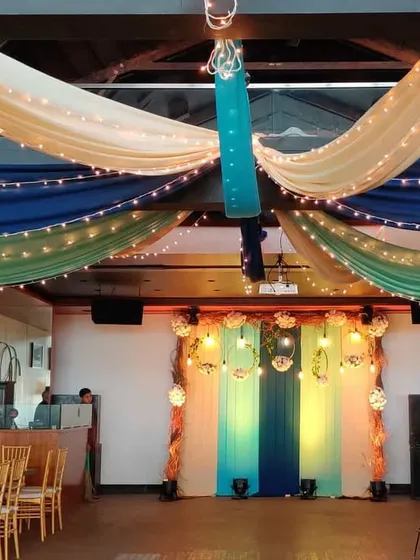 A full view of the indoor Mehendi party setup. The colorful ceiling drapes and the stylish photo backdrop come together to create a cohesive and fun party environment.