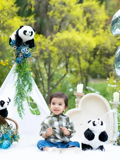 Celebrating a second birthday with an outdoor panda-themed party in the studio. The lush green background and blue accents create a vibrant and fun atmosphere.