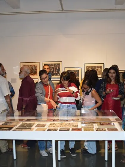 Visitors gathered around the vitrine of archival materials at the 'Hand Prints' preview.