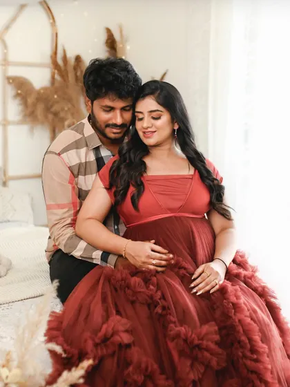 An intimate couple's portrait in a warm, boho chic studio setting. The rich red of her dress adds a pop of color and romance.