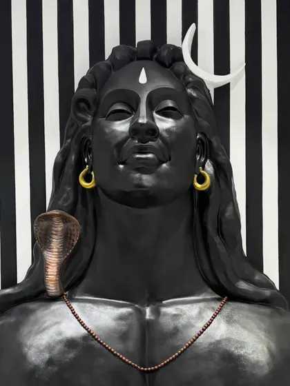 A close-up of the Adiyogi sculpture's face. This shot highlights the smooth finish of the fiber material and the precision of the hand-painted details, from the tilak to the serene expression.