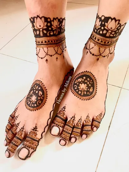 A beautiful foot mehendi with a central lotus mandala. The design covers the toes and extends to the ankle, creating a lovely pattern.