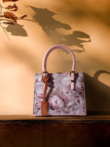 A beautiful shot using light and shadow to create a dramatic effect. The shadow of leaves falls across a floral handbag, adding depth and artistry to the composition.