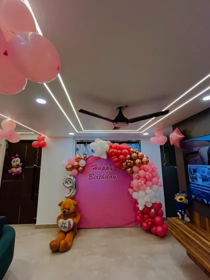 A wider shot of the room, showing the birthday backdrop and additional balloons on the ceiling.
