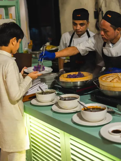 A chef serves a young guest at our live dim sum counter, showcasing our family-friendly service.