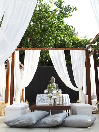 A serene outdoor lounge setup with white drapes and plush cushions. This is an ideal setting for a relaxed Mehendi or a pre-wedding brunch, allowing guests to enjoy the open air in comfort and style.