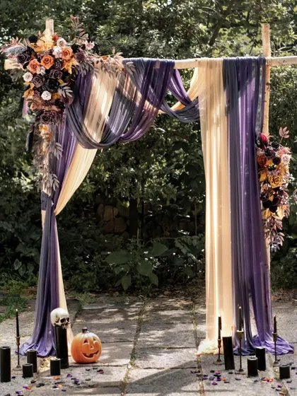 This unique wedding arch uses a dramatic color palette of deep purple and cream, accented with autumn florals. The addition of a jack-o'-lantern and black candles gives it a gothic, Halloween-inspired romantic feel.