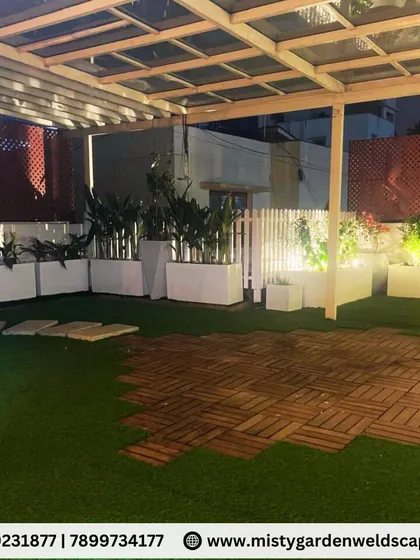 This wide shot shows the full terrace garden layout, with a combination of artificial grass and WPC deck tiles creating distinct zones for planting and seating.