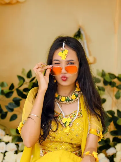 A fun and quirky portrait of the bride-to-be at her Haldi, posing with sunglasses and a playful expression.