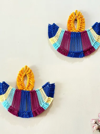 A pair of colorful macrame diya hangings. These are a modern, reusable alternative to traditional diyas and add a festive touch to your walls during Diwali.