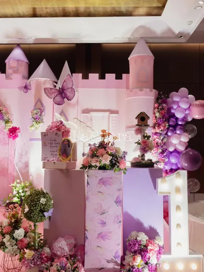 A side view of the princess castle stage, showing the layered decor with a light-up 'ONE' sign and floral arrangements.