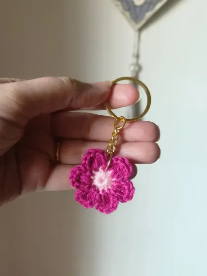 A magenta floral keychain with a light pink center.