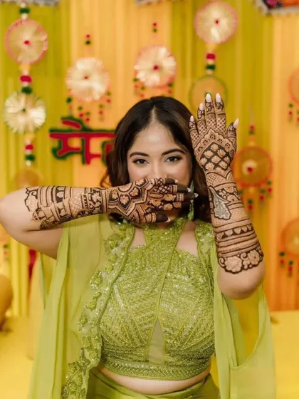 A playful pose from a happy client at her mehendi ceremony. Her full-arm mehendi is the star of her look.
