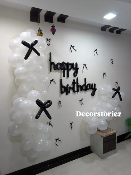 For a minimalist and modern look, I can create simple wall decorations like this one using white balloons with black balloon accents and a 'happy birthday' cutout.